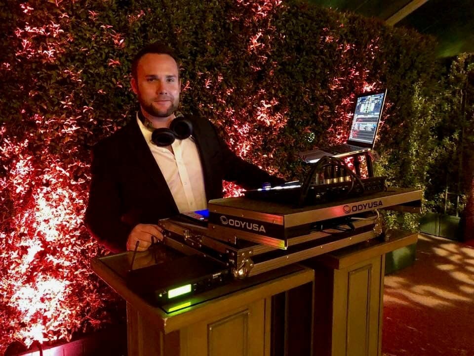 Ryan Damron behind the DJ booth at a red-lit event